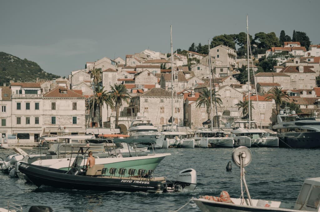 Hvar harbour in Croatia: stone houses and red-tiled roofs above the water with boats and yachts