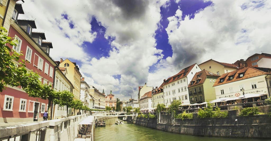 Ljubljanica River through Ljubljana with colourful facades and the pink Franciscan church in the distance